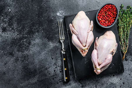 Farm eco friendly raw quails ready for cooking. Black background. Top view. Copy space.