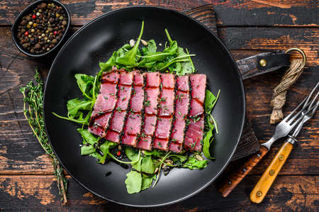 Grilled teriyaki Tuna steak salad with arugula and spinach. Dark wooden background. Top view.の写真素材