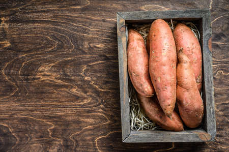 Raw Sweet potato on Wooden table. Wooden background. Top view. Copy space.の写真素材