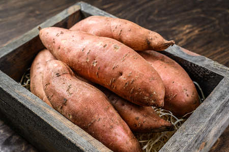 Raw batata Sweet potato on Wooden table. Wooden background. Top view.
