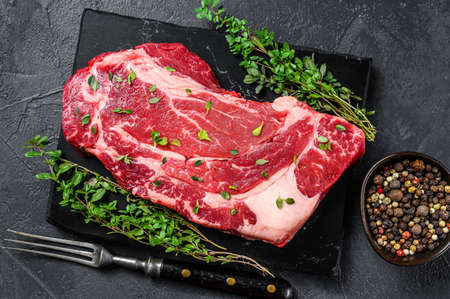 Raw Organic chuck eye roll meat steak cuts. Black background. Top view.の写真素材