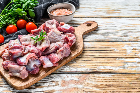 Raw uncooked Bird chicken giblets gizzards, stomachs on a cutting board. wooden background. Top view. Copy space.の写真素材
