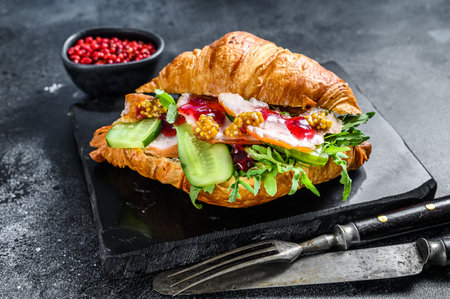 Croissant sandwich with cheese, arugula and ham. Black background. Top view.の写真素材