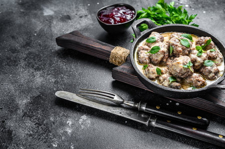 Beef meatballs in cream sauce in a frying pan. Black background. Top view. Copy space.の写真素材