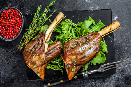 Stew goat Shanks on a marble board with arugula. Black background. Top view.の写真素材