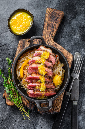 Grilled duck meat breast fillet steak with noodles and tangerines sauce. Black background. Top view.の写真素材