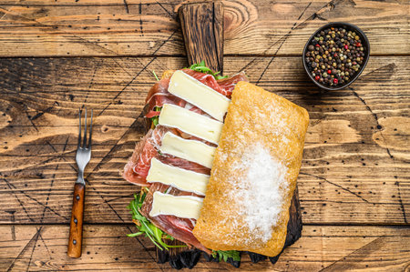 Parma Ham Sandwich on ciabatta bread with arugula and camembert brie cheese. wooden background. Top view.の写真素材