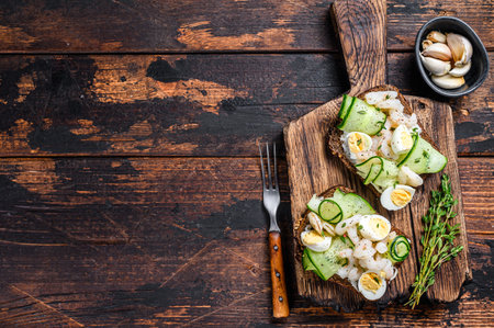 Sandwiches with shrimp, prawns, quail eggs and cucumber on rye bread. Dark Wooden background. top view. Copy space.の写真素材