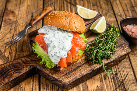 Sandwich with salted fish salmon, avocado, burger bun, mustard sauce and Iceberg salad. wooden background. top view.の写真素材