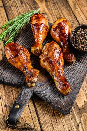 Barbecue roasted chicken drumsticks on a wooden cutting board. wooden background. top view.の写真素材