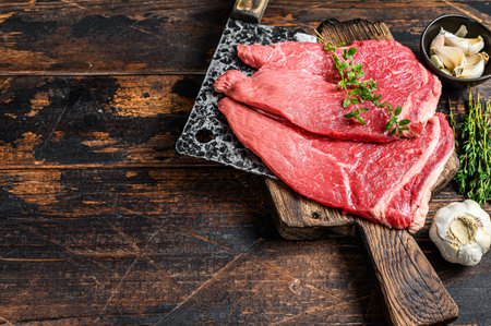 Raw veal meat chop steak. on a cutting board Dark wooden background. Top view. Copy space.の写真素材