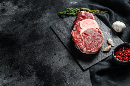Osso Buco meat. Raw cross cut veal shank and seasonings for cooking Osso Buco. Black background. Top view. Copy space.の写真素材