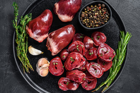 Sliced Raw turkey hearts ready for cooking. Black background. Top view.