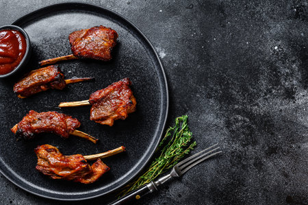 BBQ grilled sliced veal short spare loin ribs. Black background. Top view. Copy space.の写真素材