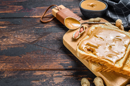 Crispy toast with peanut butter on breakfast. Dark Wooden background. Top view. Copy space.