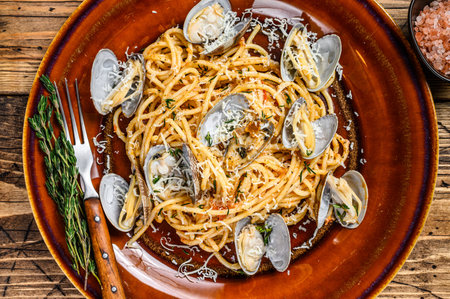 Italian seafood Spaghetti pasta with clams in a rustic plate. Wooden background. Top view.の写真素材