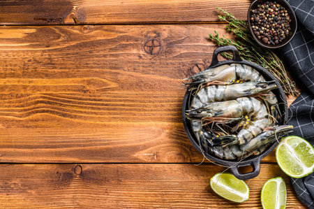 Fresh tiger shrimps, prawns with spices and herbs in a pan. wooden background. Top view. Copy space.の写真素材