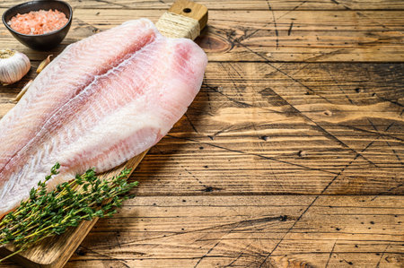 Raw fillet of white fish catfish. wooden background. Top view. Copy space.の写真素材