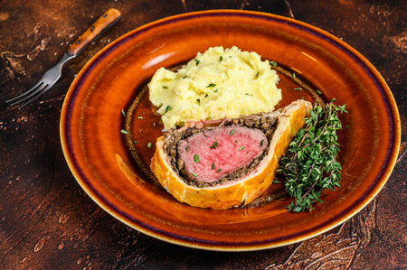 Beef Wellington pastry with mushed potato on a rustic plate. Dark background. Top view.の写真素材