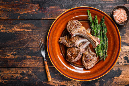 BBQ grilled lamb mutton meat chops steaks on a plate. Dark wooden background. Top view. Copy space.の写真素材