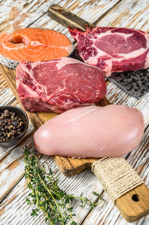 Fresh raw beef striploin steak, chicken breast fillet, pork and salmon steak. White wooden background. Top view.の写真素材