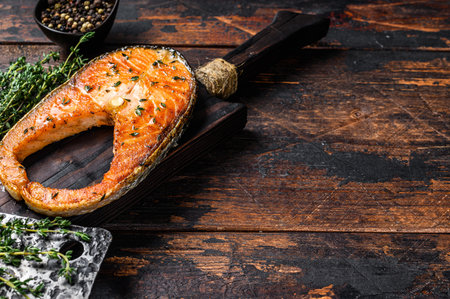 Fried trout fillet steak with pepper. Dark wooden background. Top view. Copy space.の写真素材