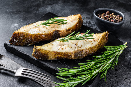 Halibut fish steak with rosemary. Black background. Top view.の写真素材