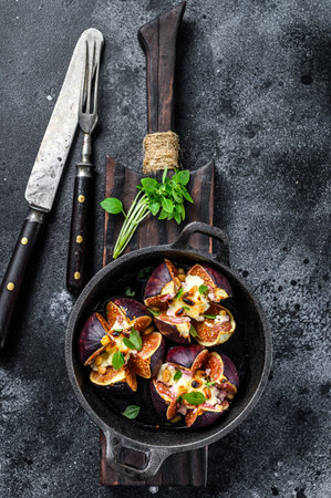 Baked figs with goat cheese, vermouth, honey and walnuts. Black background. Top view.の写真素材