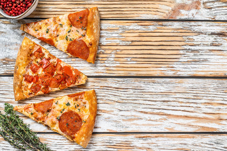 Pieces of pepperoni and tomato pizza. White wooden background. Top view. Copy space.の写真素材