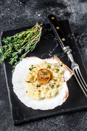 Risotto with pan seared sea scallops in a shell. Black background. Top view.の写真素材