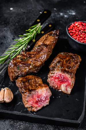 Grilled brisket steaks in bbq sauce on a marble board. Black background. Top view.の写真素材