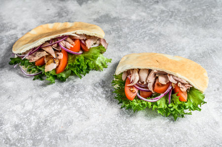 Doner kebab with grilled chicken meat and vegetables in pita bread. Gray background. Top view.