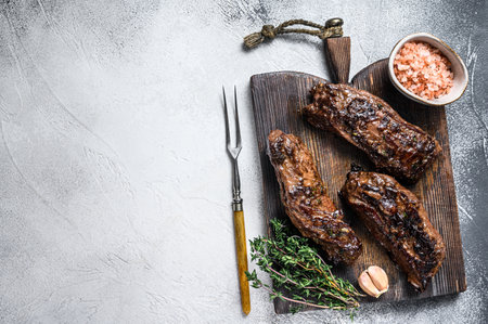 Grilled brisket steaks in bbq sauce on a wooden board. White background. Top view. Copy space.の写真素材