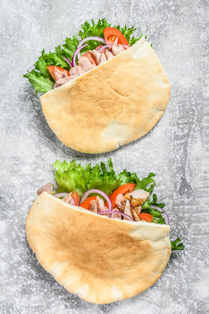 Doner kebab with grilled chicken meat and vegetables in pita bread. Gray background. Top view.の写真素材