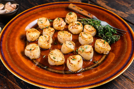 Fried scallops with butter spicy sauce in a plate. Dark wooden background. Top view.の写真素材