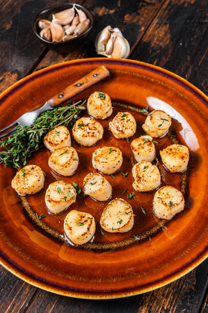Fried scallops with butter spicy sauce in a plate. Dark wooden background. Top view.の写真素材