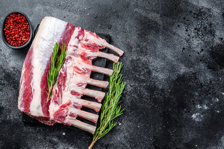 Raw fresh rack of lamb meat on marble board. Black background. Top view. Copy space.の写真素材