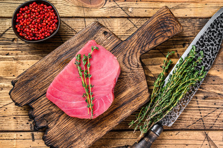 Fresh Raw tuna steak on a wooden cutting Board with knife. wooden background. Top view.の写真素材