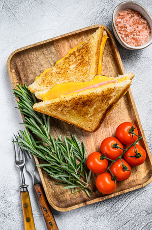 Homemade fried ham and cheese sandwich on a cutting board. White background. Top view.の写真素材
