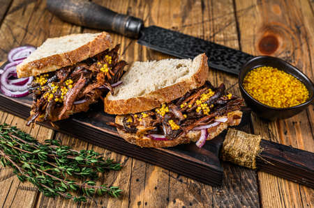 Sandwich with slow smoked pulled pork meat on white bread. wooden background. Top viewの写真素材