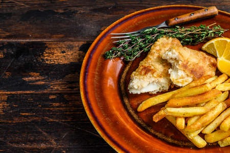 Fish and Chips british fast food with french fries and tartar sauce on a rustic plate. Dark wooden background. Top view. Copy spaceの写真素材
