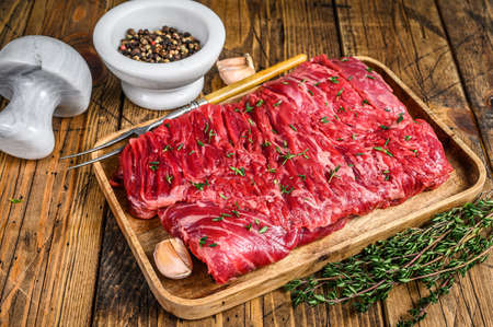 Raw beef round cut meat on a wooden tray with herbs. wooden background. Top viewの写真素材