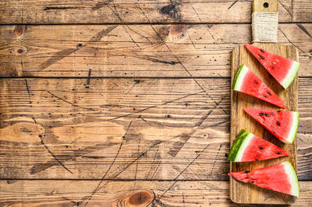 Heap of fresh red sliced watermelon. Wooden background. Top view. Copy spaceの写真素材