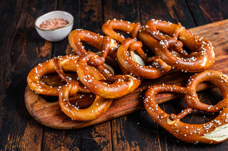 Homemade Soft Pretzels with Salt on a wooden board. Dark wooden background. Top view