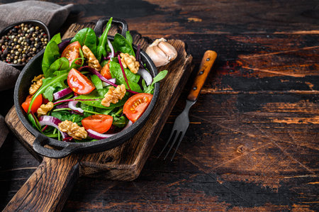 Healthy bistro green salad with mix leaves mangold, swiss chard, spinach, arugula and nuts in a pan. Dark wooden background. Top view. Copy spaceの写真素材