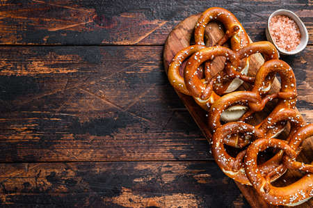 Homemade Soft Pretzels with Salt on a wooden board. Dark wooden background. Top view. Copy spaceの写真素材