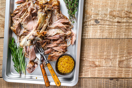 Roast pork knuckle eisbein meat on a baking pan with herbs. Wooden background. Top view. Copy space