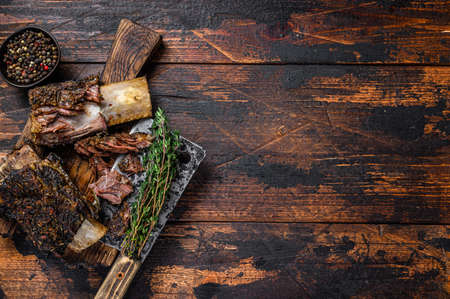 BBQ short chuck beef ribs with herbs and meat cleaver. Dark wooden background. Top view. Copy spaceの写真素材