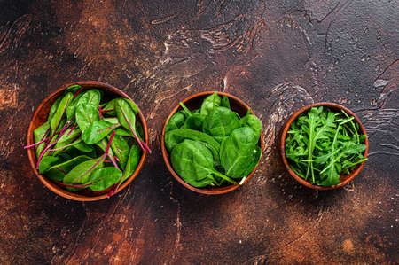 Mix Salad leafs, Arugula, Spinach and swiis Chard in wooden bowls. Dark background. Top viewの写真素材