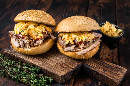 Pulled pork burger with bbq sauce and coleslaw salad. Dark wooden background. Top view